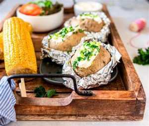 Home Drievoudig gepofte aardappel garneerd met gebakken aardappelschillen, cheddar en spek in een gietijzeren pot