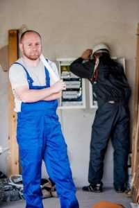 Home Elektricien controleert aansluitingen van een oude groepenkast op schade en corrosie